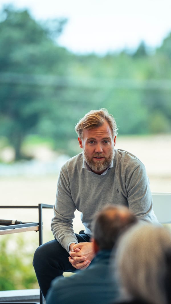 Bilde av Anders Pedersen som snakker til en forsamling med natur i bakgrunnen.